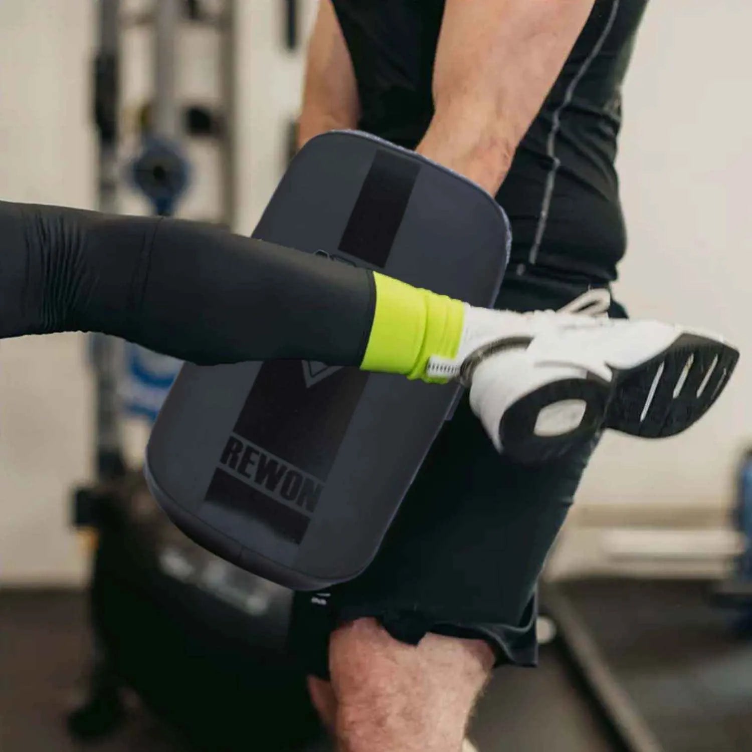 Athlete kicking Schlagpolster pad in a gym, showcasing Rewon training gear for MMA, kickboxing, and fitness workouts.
