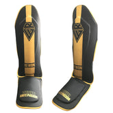 Rewon Classic Schienbeinschoner in Schwarz/Gold aus Kunstleder, ideal für Kickboxen und Muay Thai, mit Klettverschluss und Gummizug.