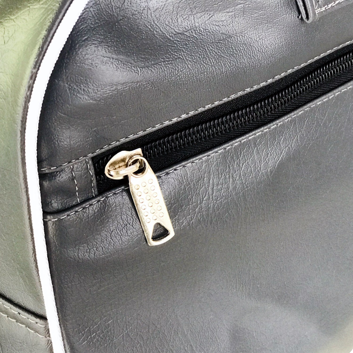 Close-up of a gray sports bag's side pocket zipper, ideal for boxing accessories and fitness gear. Durable and stylish design.